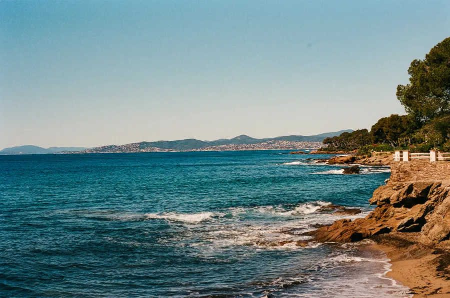 La côte, de loin — La côte vue du sentier, l'eau turquoise et la roche rouge qui plonge dedans.
