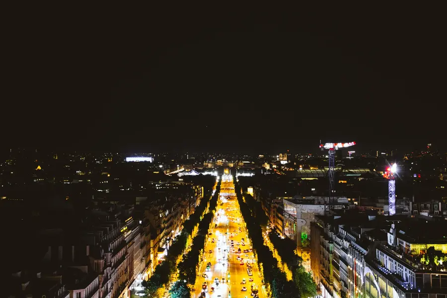 Les Champs-Élysées — L'avenue vue d'en haut, la nuit, réduite à deux traînées de lumière.