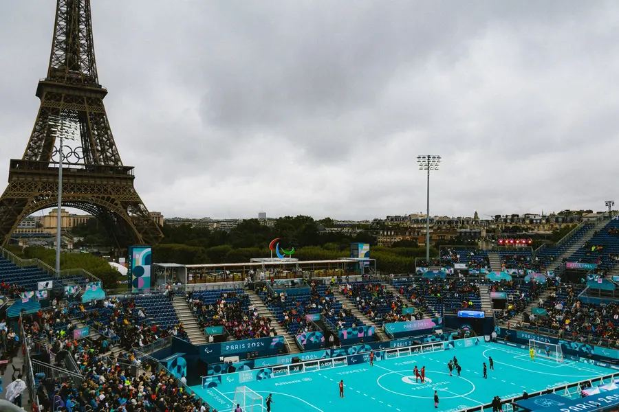 La tour et l'arène — Septembre, les Paralympiques. Le terrain de cécifoot au pied de la tour, sous un