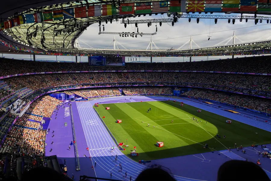 Le Stade de France, d'en haut — Le stade vu du dernier rang : la piste violette, la pelouse, et les drapeaux tou