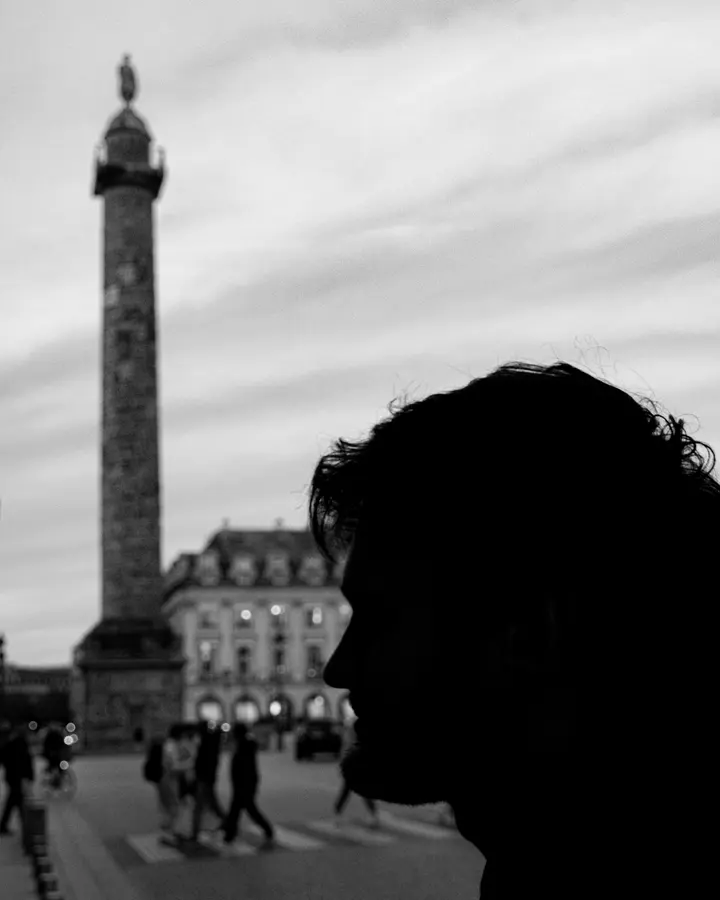 Le profil — Une silhouette au premier plan, la colonne Vendôme derrière. Deux échelles dans 