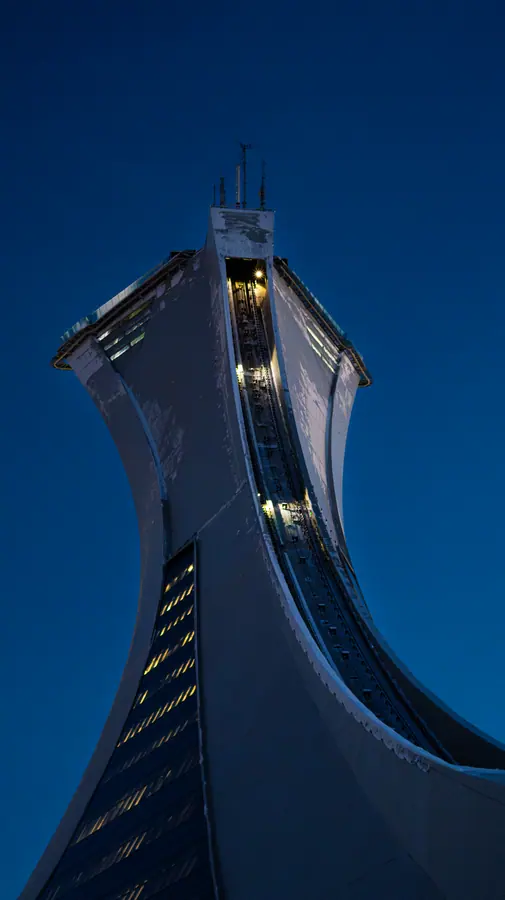 Heure bleue — Le mât olympique à l'heure bleue, les fenêtres allumées en pointillé le long de 