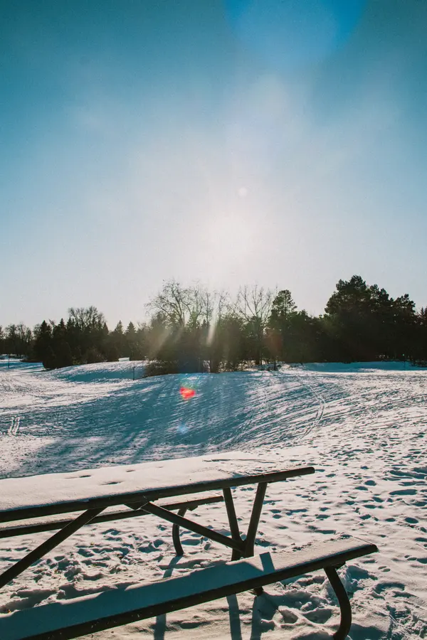 La table — Une table de pique-nique sous la neige, à contre-jour. L'été rangé pour six mois