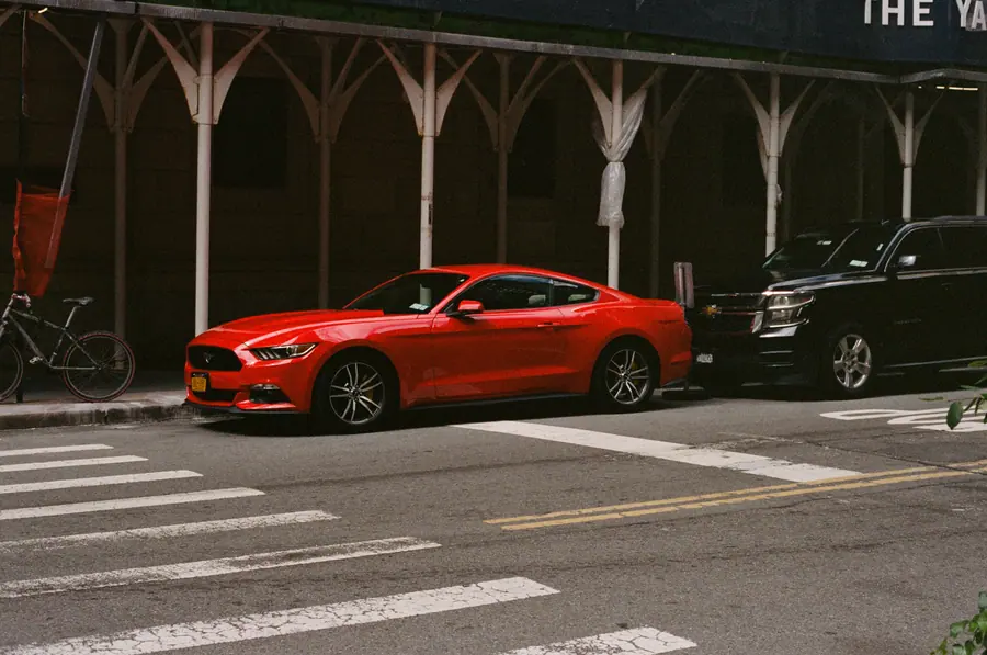 La Mustang — Une Mustang rouge garée sous une arcade néogothique. Le rouge est la seule coule