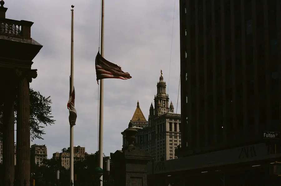 Le drapeau en berne — Deux mâts, un drapeau à mi-hauteur, la tour de Manhattan Municipal Building derr